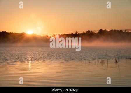 Morning fog and sunrise at Lower Togue Pond, in Baxter State Park, Maine Stock Photo