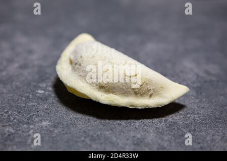 Single polish gluten-free dumpling (Pierogi), polish national dish made of dough and savoury or sweet filling. Close-up view . Stock Photo