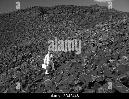 Businessman dressed in all white walking in an ominous, dark background of boulders. Stock Photo