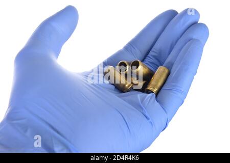 several spent shell casings in a hand wearing a blue rubber glove Stock Photo