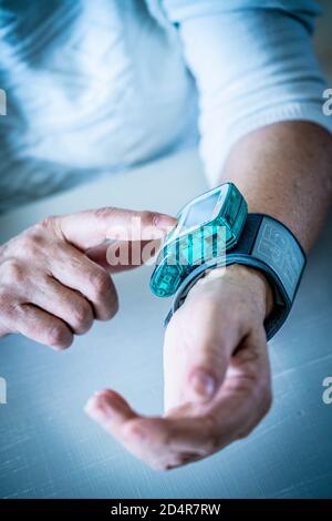 Woman taking her blood pressure with a portable blood pressure monitor. Stock Photo