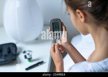 A diabetic child is checking her blood sugar level (self glycemia). Stock Photo
