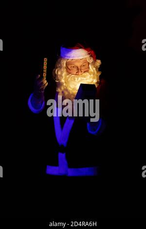 Male actor dressed as Santa Claus posing on a dark red background. Stock Photo