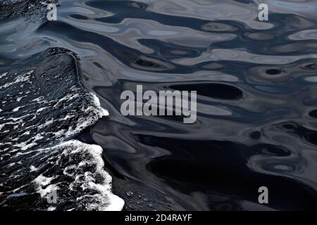 Detail of a wave foam on dark water Stock Photo