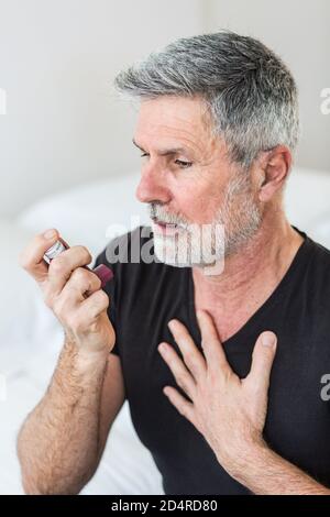 Man using an inhaler during an asthma attack. Stock Photo