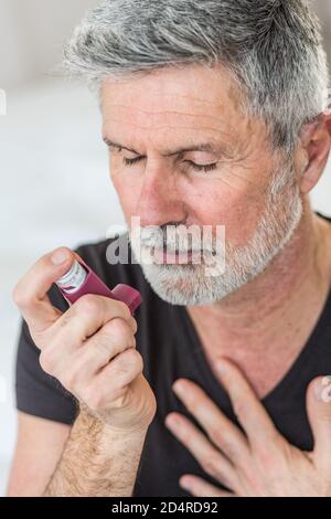 Man using an inhaler during an asthma attack. Stock Photo