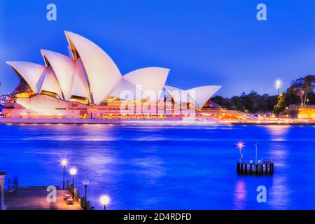 Sydney, Australia - 26 September 2020: Sydney Opera house at sunset with bright illumination on shores of Sydney harbour - side view. Stock Photo