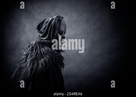 Ghostly figure in hooded cloak in the dark Stock Photo