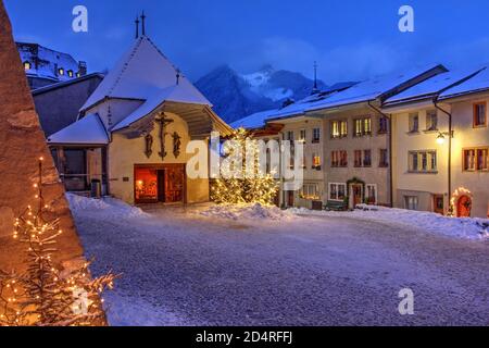 Winter (Christmas) night scene in the medieval town of Gruyeres, district of Gruyere, Fribourg canton, Switzerland. The town gave the name to the famo Stock Photo