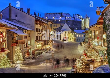 Winter (Christmas) in the medieval town of Gruyeres, Fribourg canton, Switzerland. In the background looming over is the Chateau de Gruyere. Stock Photo