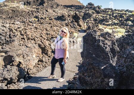 Cute stylish blond woman hiker with a camera poses on the trail in Lava Lands Newberry Volcano National Monument Stock Photo