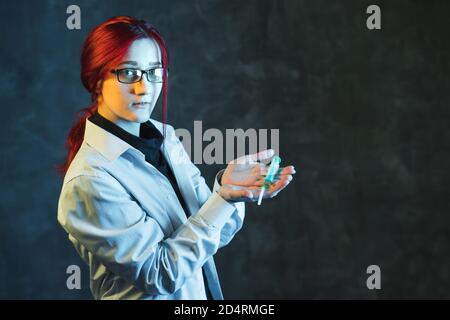 Red-haired girl doctor shows syringe with vaccine. Virus protection concept with copy space. Stock Photo