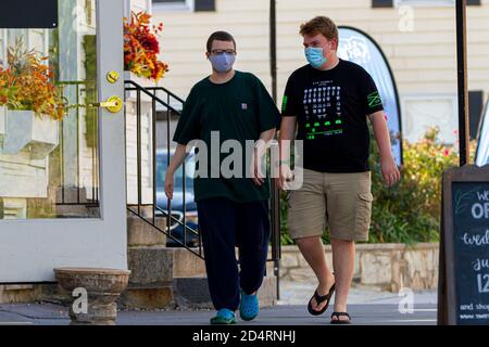 Ellicott City, MD, USA 10/07/2020: Two young men both wearing face masks due to COVID-19 are walking in the street. They have casual summer outfit. Co Stock Photo
