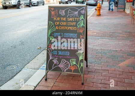 A black chalkboard style sandwich board in front of a Restaurant at historic Ellicott City. The board has regulations for customers  as face masks. Stock Photo