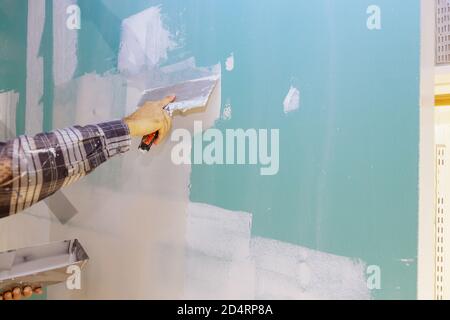 Closeup of a man aligning a wall with spatula and plastering gypsum cardboard wall Stock Photo