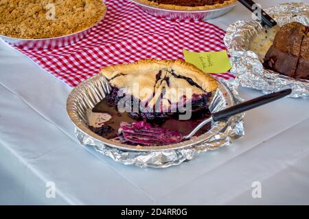 Home made baked goods are sold at a festival, by the slice. An apple crumb pie, pecan, banana bread, and fresh blueberry pie. Stock Photo