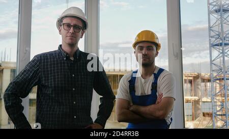 Builders working team looking to camera at construction site. Stock Photo