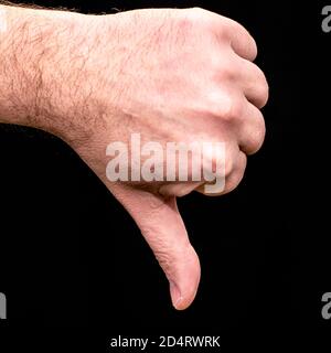 male palm clenched into a fist thumb pointing down on a black background gesture dislike Stock Photo