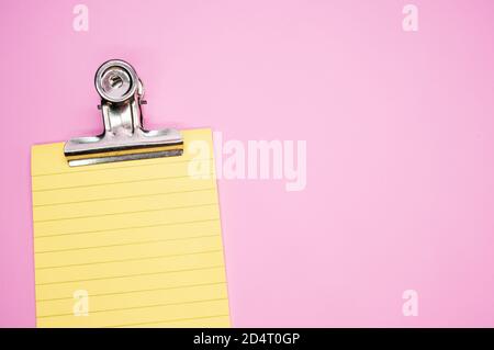 Top view of a notepad with a paper clipper isolated on a pink background Stock Photo