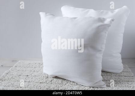 Two white pillows on a fluffy rug. Objects on a wooden surface. Stock Photo