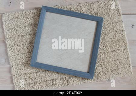 Blue photo frame on a fluffy white rug. Objects on a light wooden surface. Stock Photo