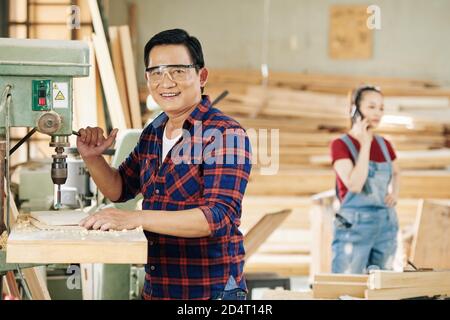 Carpenter drilling holes in plank Stock Photo