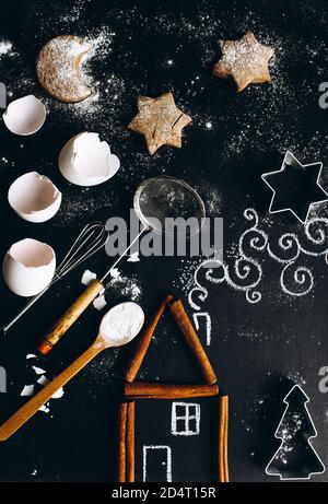Cinnamon house on the table is complemented by a chalk pattern and utensils for making cookies. Stock Photo