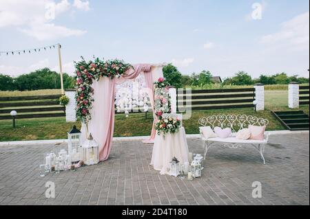 Wedding arch made of fabric and fresh flowers, roses, hydrangeas, eustoma, greenery and eucalyptus. Stock Photo
