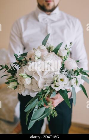 Elegant delicate bouquet of the bride made of white peonies, hydrangeas, roses and green branches. Stock Photo