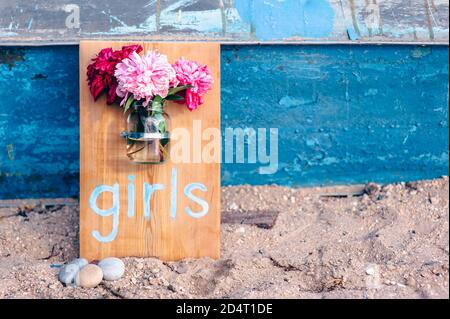 Wooden board with inscription girls and a vase attached to the board with peonies. Stock Photo