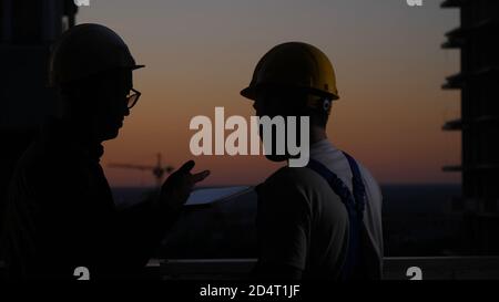 Construction workers using digital tablet at sunset. Stock Photo