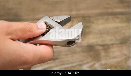A key in the hand of a technician. Wooden Background Stock Photo