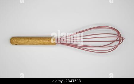 Top down view on one isolated whisk with wood handle and pink wire loops on blank white background Stock Photo