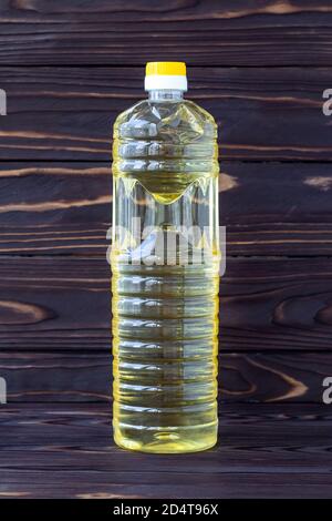 Sunflower oil in a plastic bottle on dark wooden boards, yellow salad-oil, transparent packaging. Healthy organic product. Food ingredient, vegetable Stock Photo