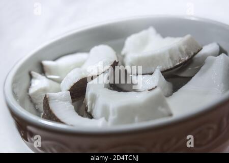 Detail of some pieces of fresh coconut immersed in water inside a bowl Stock Photo