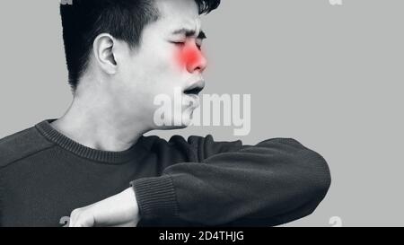 Asian man showing correct sneezing, coughing in his elbow Stock Photo