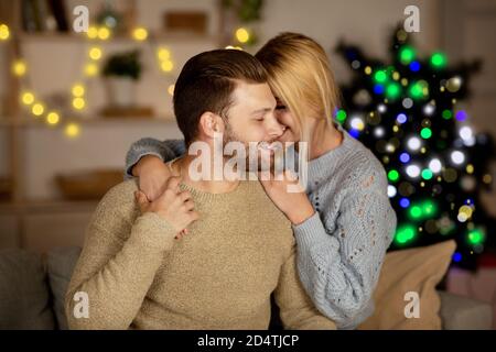 Young lovers cuddling at home, celebrating Christmas Stock Photo