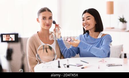 Asian Woman Doing Makeup For Her Beautiful Model Stock Photo