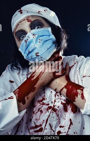 gloomy bloody woman doctor on a black background looking at camera Stock Photo