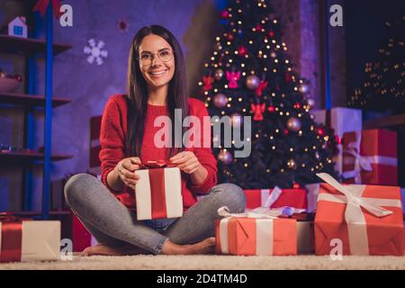 Photo portrait of girl sitting on floor in lotus pose holding gift box indoors Stock Photo