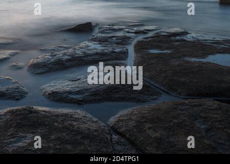 Twilight sunset over rocky shore of Baltic sea. Almost clear sky and orange strap along the horison. Estonia. Stock Photo