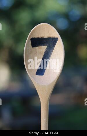 Portrait image of wooden spoon painted with the number seven Stock Photo