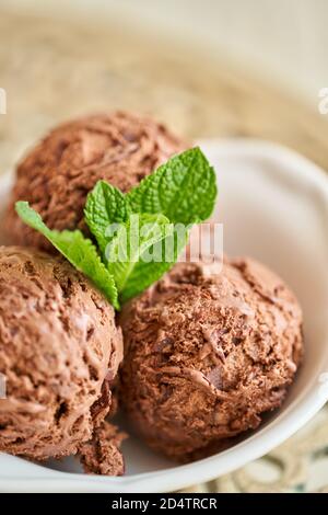 Chocolate ice cream with mint leafe. three balls in a white bowl on a vintage table. Stock Photo