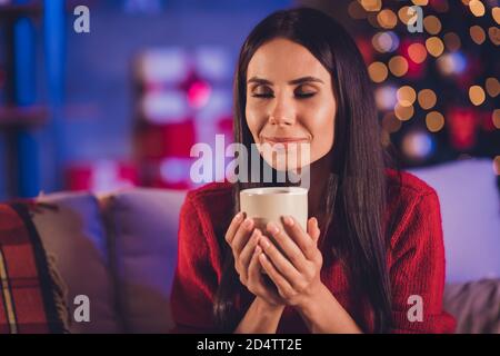 Photo portrait of woman smelling aroma of fresh drink holding cup with two hands in house with christmas decoration Stock Photo