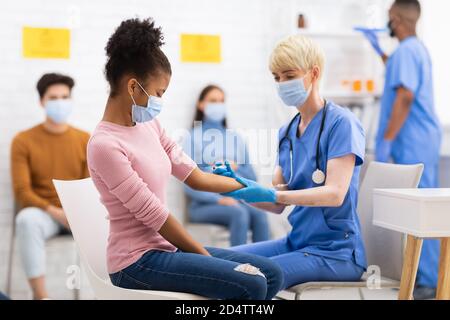 Nurse Vaccinating African Girl Against Covid-19 Injecting Vaccine In Hospital Stock Photo