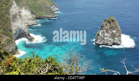 Scenic view of clear turquoise blue sea and rocky coastline with green foliage in foreground on Nusa Penida Island, Bali, Indonesia Stock Photo