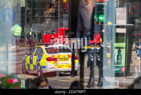 A West Midlands Police BMW traffic car reflects in the window of Marks and Spencer on the High Street, Birmingham Stock Photo