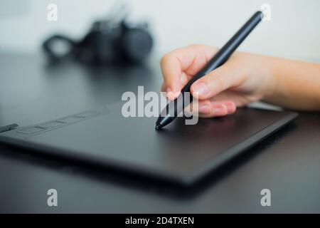 Graphic designer or photographer using digital tablet and computer. Graphic tablet and hand holding stylus close up. Copy space. Stock Photo