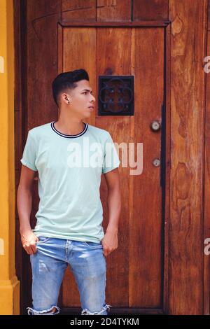 Vertical shot of Hispanic young man leaning against the door Stock Photo