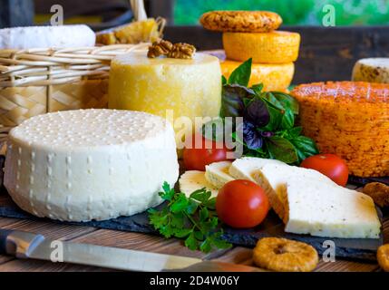 Cheese Heads with cheeses of different kinds. Assortment of different cheese types on wooden background. Fresh dairy product, various greens, nuts, honey, healthy organic food. Delicious apetizer. Countryside market. Home-made cheese. Stock Photo